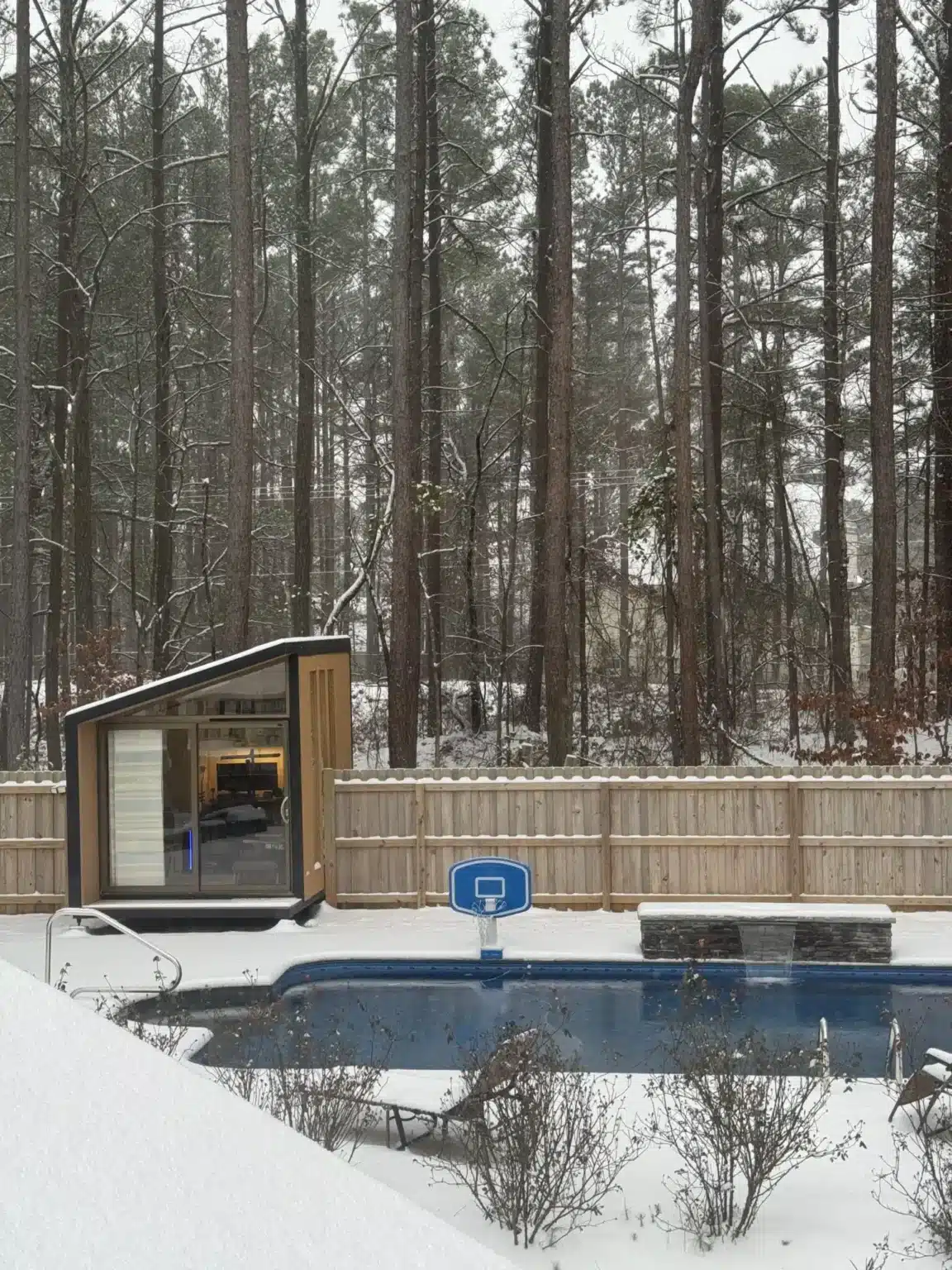 Autonomous WorkPod in backyard covered with snow during winter beside a frozen pool
